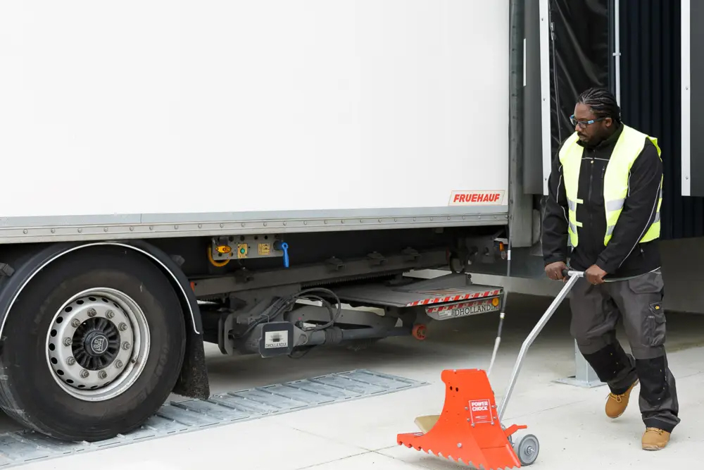 Truck-driver-moves-wheel-chock-with-dolly